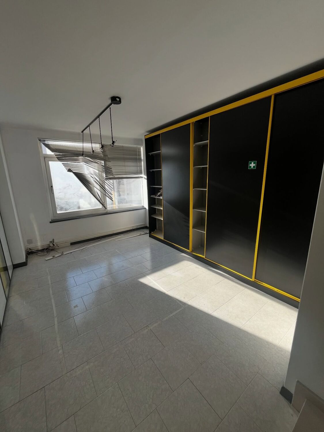 Parede de armários escuros numa sala com janela